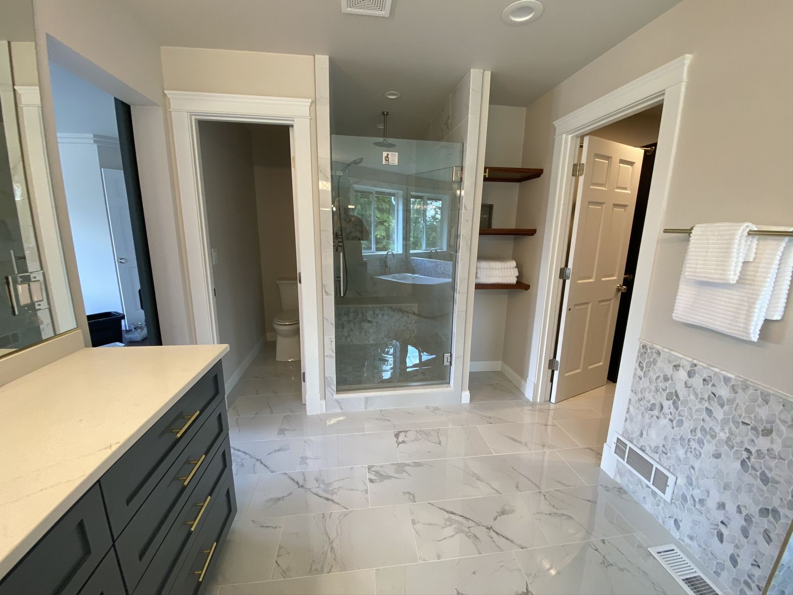 Remodeled master bathroom with freestanding tub and marble tile
