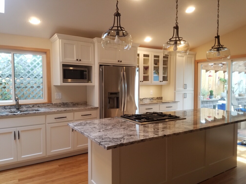 Remodeled kitchen with white cabinets, granite counters, and new appliances
