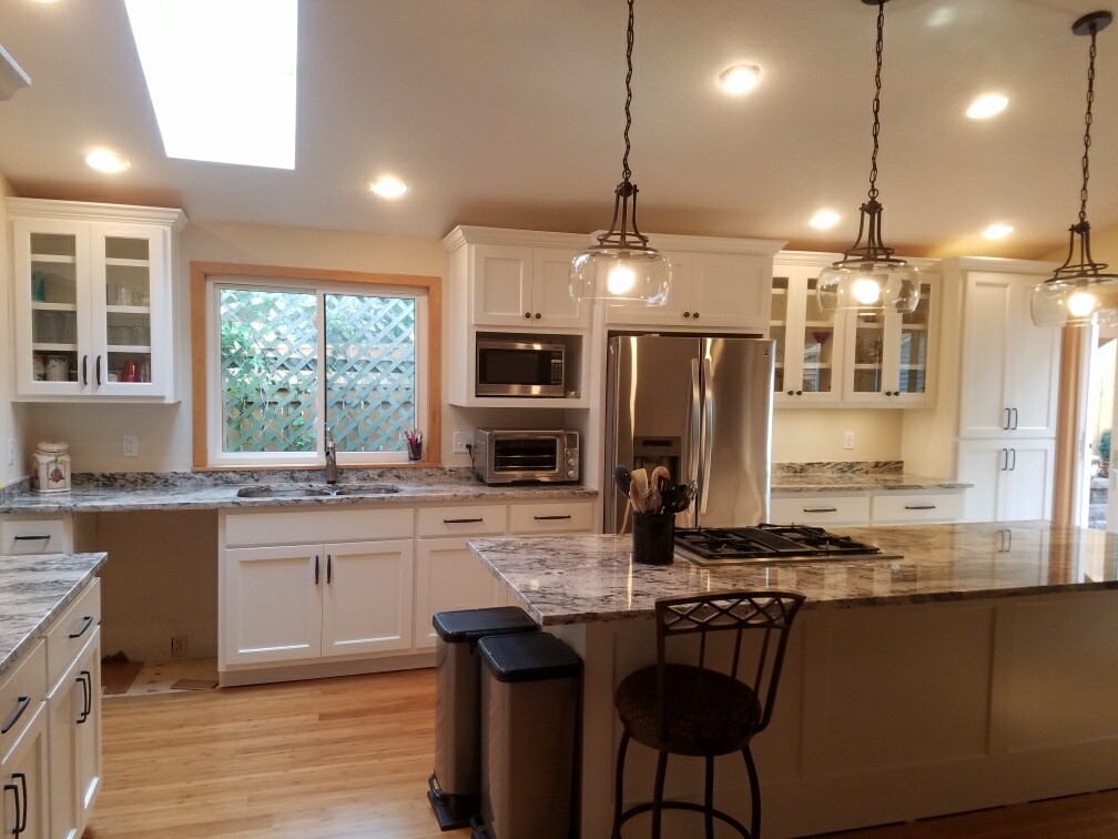 Remodeled open-concept kitchen with skylight and glass-front cabinets