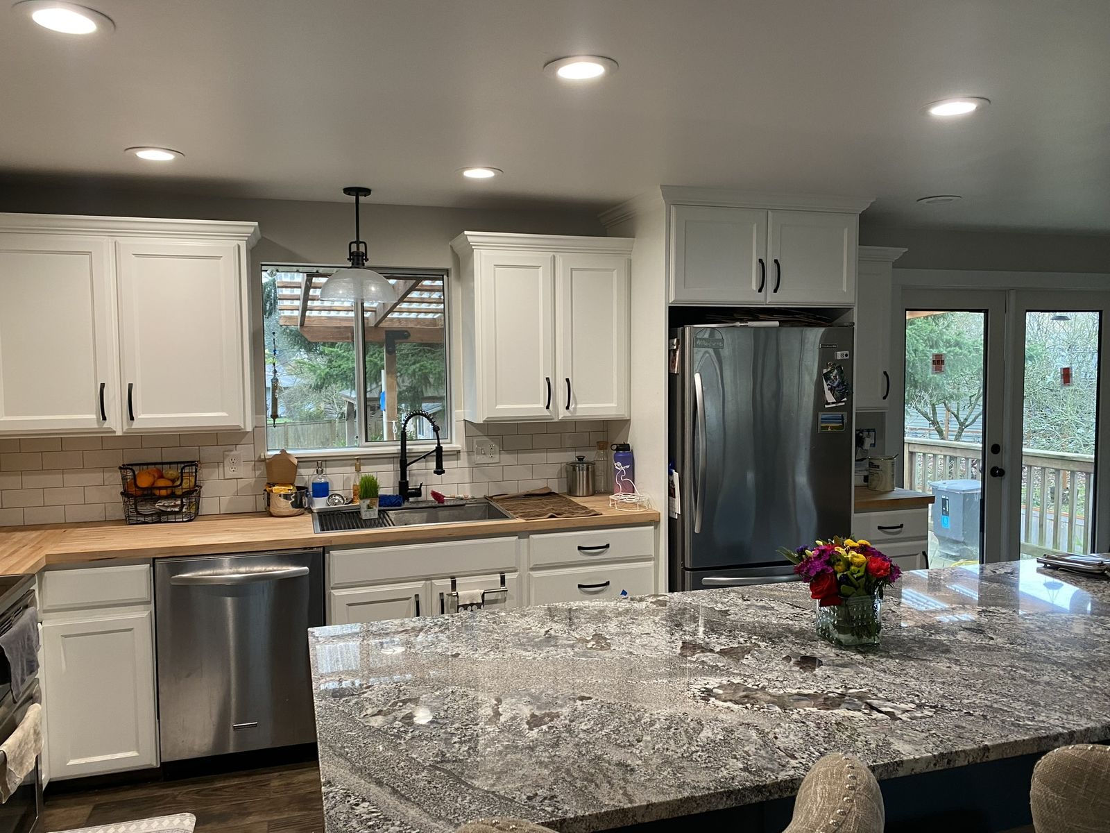 Remodeled kitchen island with blue cabinetry and upholstered barstools