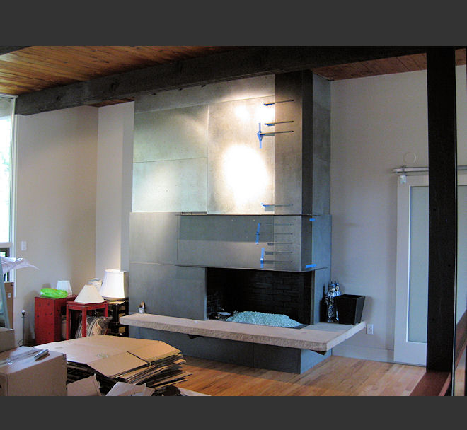 New fireplace surround pairing concrete with galvanized metal paneling after renovation