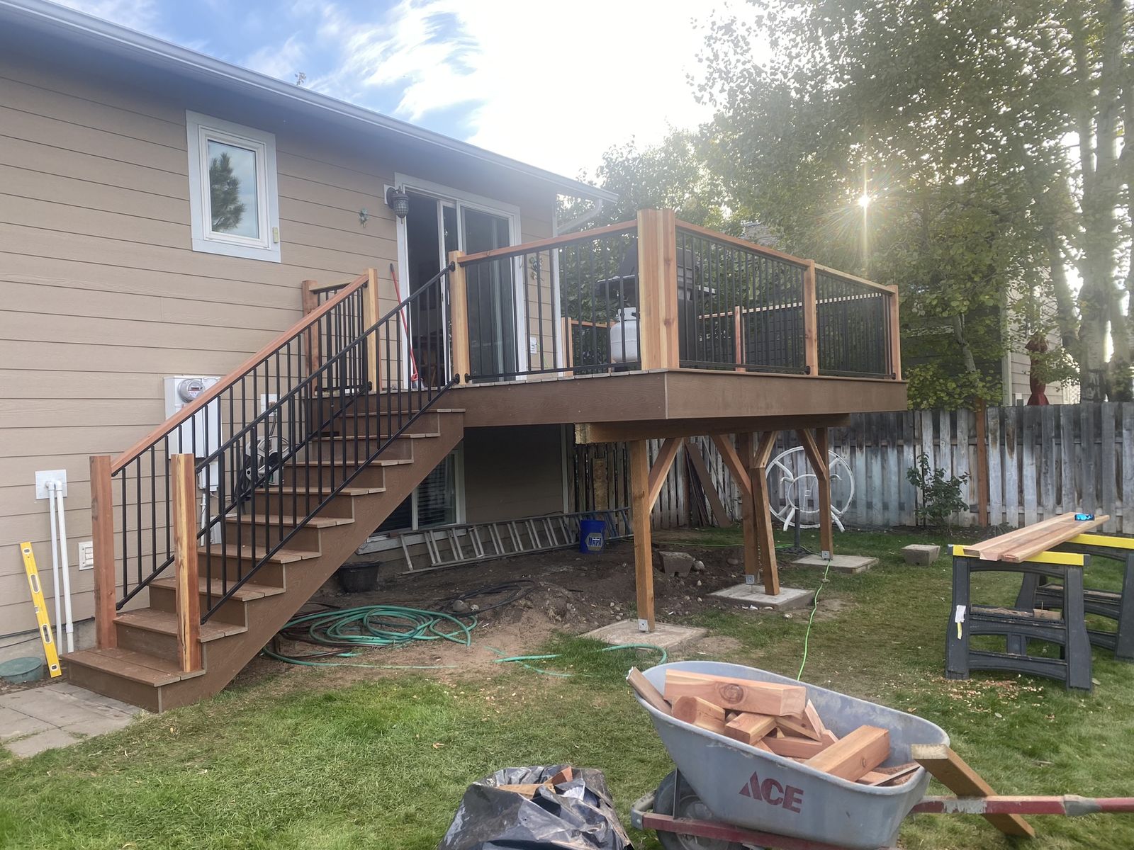Elevated second-story deck under construction with black metal railing and cedar cap rail