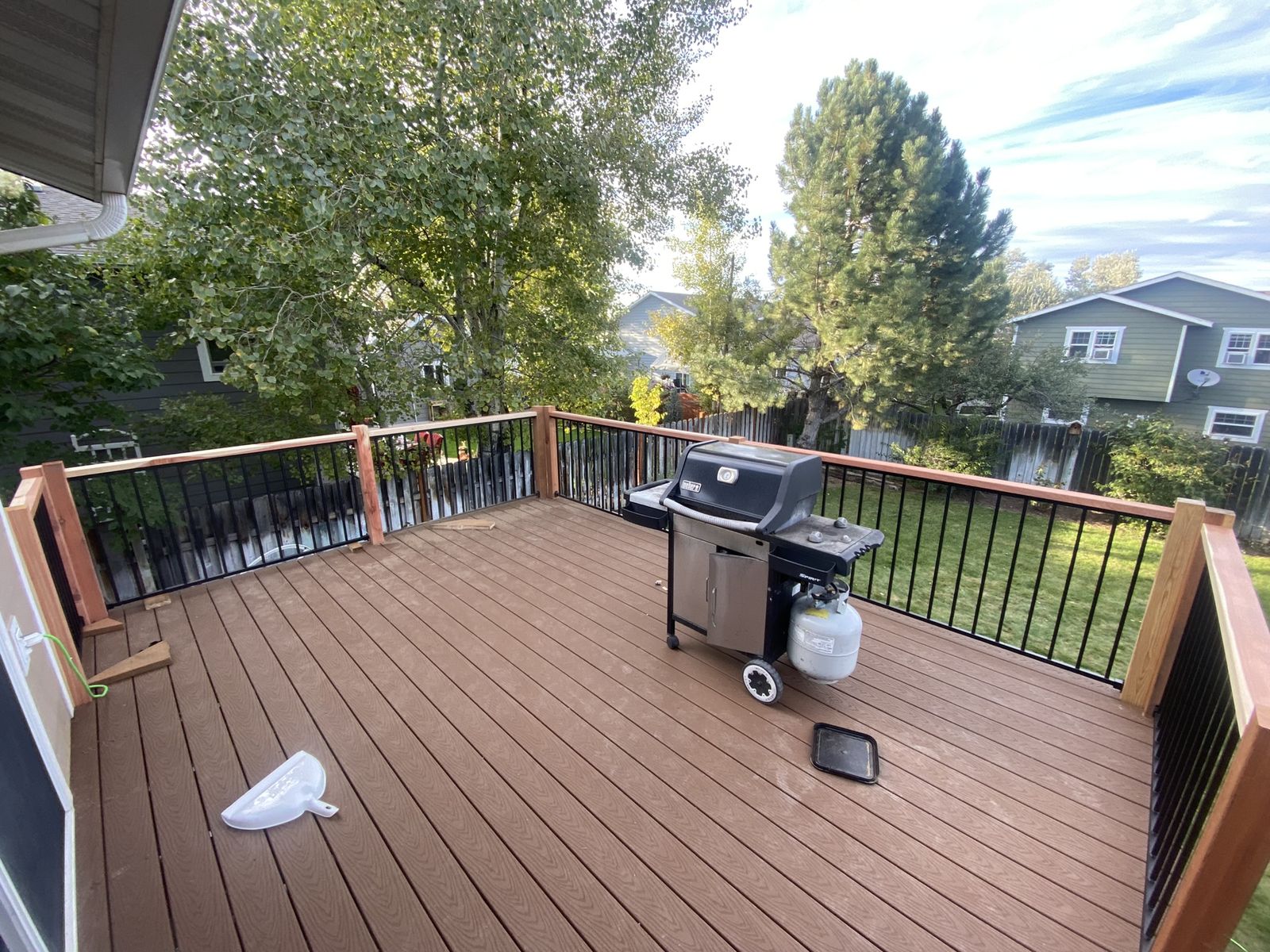 Finished elevated deck with black metal railing overlooking the backyard